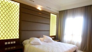 Una camera d'albergo con un letto grande, un comodino in legno e un pannello di controllo a parete.