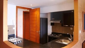 Una cucina moderna con un piano di lavoro nero, lavello in acciaio inossidabile e una porta in legno.