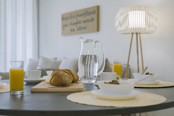 A breakfast setting with a croissant, a pitcher of water, and a glass of orange juice on a table.