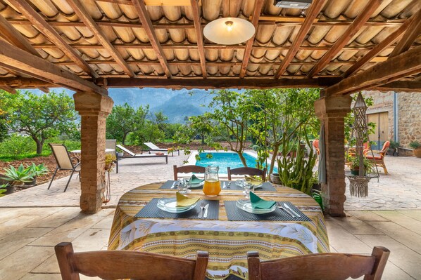 An outdoor dining area with a view of a pool and mountains.