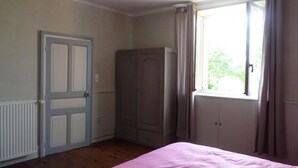 A bedroom with a bed, a wardrobe, a radiator, and a window with curtains.