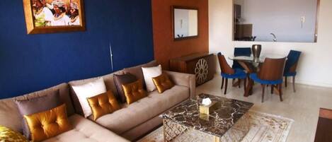 A living room with a sofa, a coffee table, and a dining area with chairs.