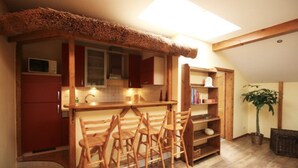 Una cocina compacta con muebles de madera, microondas integrado y una lámpara en el techo.