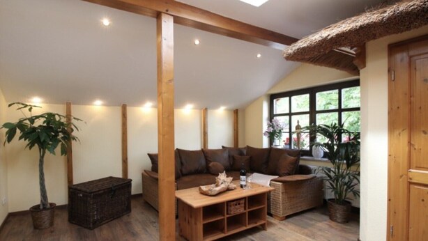 Una habitación acogedora con vigas de madera, techo de paja y un ventanal grande.