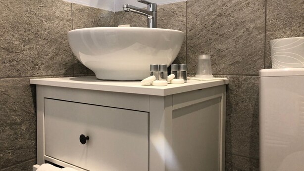 Ein modernes Badezimmer mit einem weißen Waschbecken, einem Spiegel und einer Toilette.