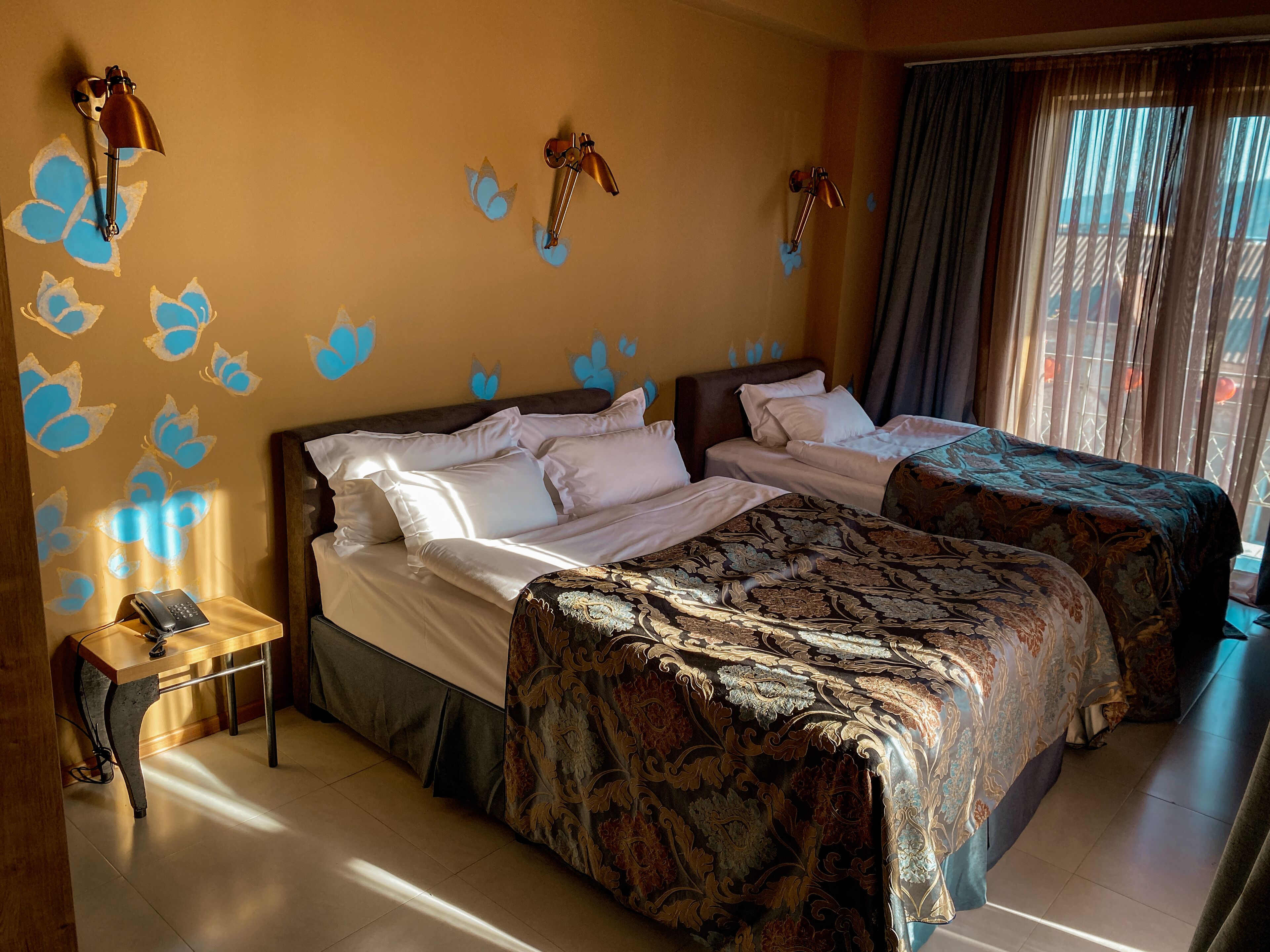 A hotel room with two beds, a bedside table with a phone, and decorative wall art.