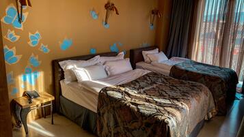 A hotel room with two beds, a bedside table with a phone, and decorative wall art.