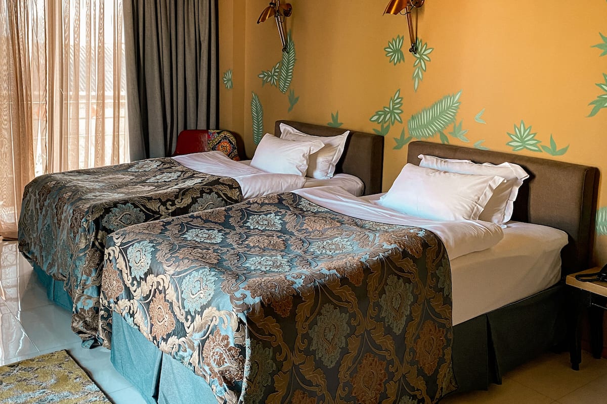 A double bed with a patterned bedspread, a bedside table, and a wall-mounted lamp.