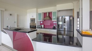 Una cocina moderna con una isla central, electrodomésticos de acero inoxidable y una pared de acento en color rosa.