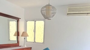Un dormitorio con cama, cómoda, espejo, lámpara colgante y equipo de aire acondicionado.