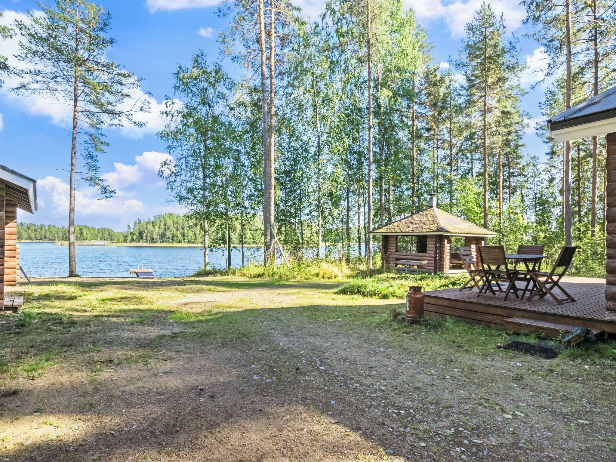 Uma cabana à beira do lago com varanda e área de estar externa.