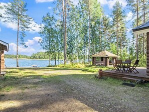 A lakeside cabin with a deck and outdoor seating area.