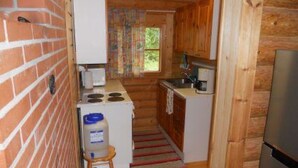 A compact kitchen with a brick wall, wooden cabinets, a small stove, and a refrigerator.