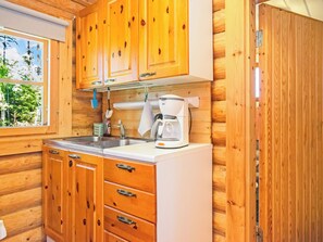 Une cuisine avec des meubles de rangement en bois, un évier et une machine à café.