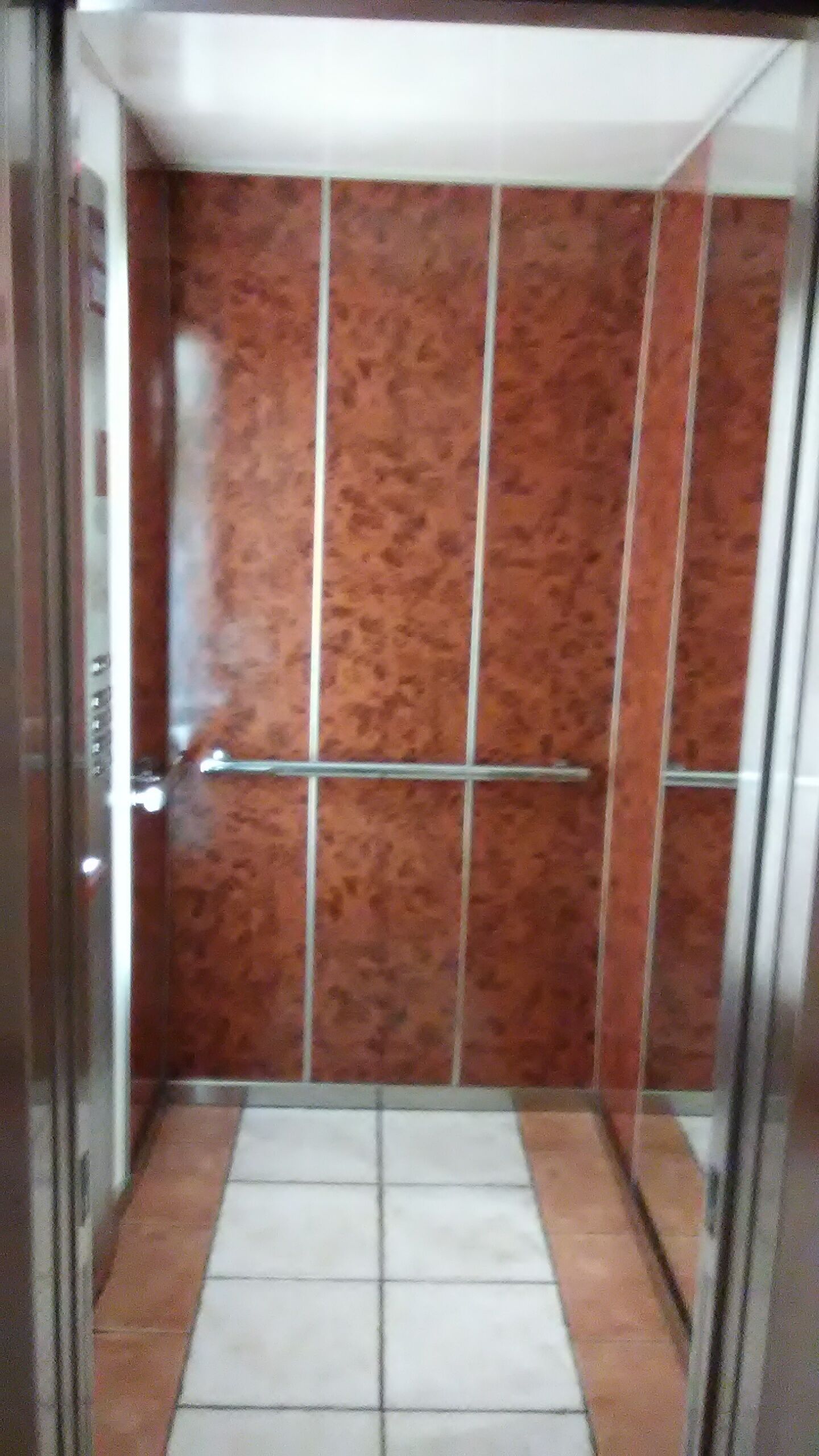 En elevator med metalgreb og flisegulv.