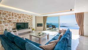 Een moderne woonkamer met een stenen muur, een flatscreen televisie, een bank en een glazen salontafel.
