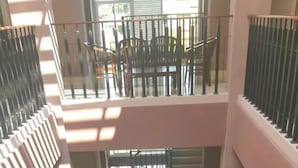A multi-level atrium with a central open space featuring a wooden table and chairs, surrounded by balconies with railings. - Hotel Amalia Malioboro (Yogyakarta)