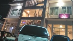 A multi-story building with a balcony on the second floor, a sign reading "Amalia," and parked cars in front. - Hotel Amalia Malioboro (Yogyakarta)