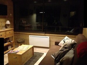 Uma sala de estar aconchegante com um sofá marrom, uma mesa de centro de madeira e uma janela com vista para o exterior.