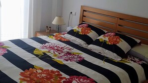 Un lit avec une couvre-lit à motifs floraux, une tête de lit en bois et une table de chevet avec une lampe.