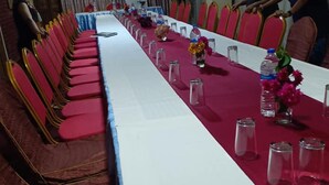 A long conference table with red chairs, water bottles, and small vases with flowers.