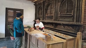 A reception desk with a wooden counter and intricate carvings on the wall behind it.