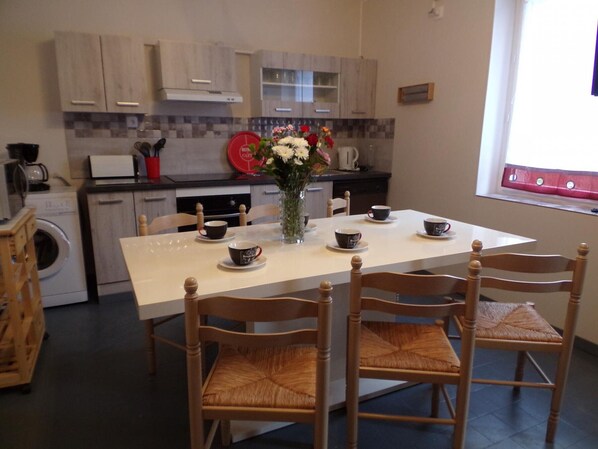 A modern kitchen with wooden cabinets, a dining table with four chairs, and a coffee station. - Contemporary 3-level house in Vaumas, near Moulins (Vaumas)