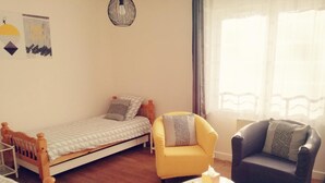 A small, cozy room with a single bed, a yellow armchair, a dark armchair, and a small round table with a yellow object on it. - Contemporary 3-level house in Vaumas, near Moulins (Vaumas)