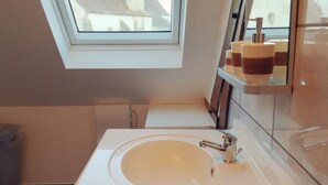 A modern bathroom with a skylight, a white sink, and a glass shower enclosure. - Contemporary 3-level house in Vaumas, near Moulins (Vaumas)