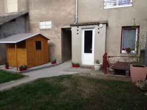 A small wooden shed with a door and a window, a white door with a small window, a metal bench, and potted plants. - Contemporary 3-level house in Vaumas, near Moulins (Vaumas)