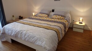 A neatly made bed with patterned bedding, a bedside table with a lamp, and a wall-mounted artwork. - Contemporary 3-level house in Vaumas, near Moulins (Vaumas)