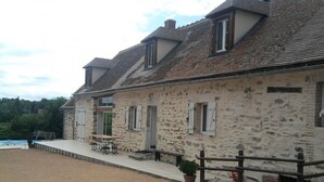 A stone building with a covered patio and a wooden fence. - Modern Rustic Cottage with Pool and Pets Allowed (Chirat-l'Église)