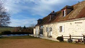 A stone building with a sloped roof, a wooden fence, and a paved driveway. - Modern Rustic Cottage with Pool and Pets Allowed (Chirat-l'Église)