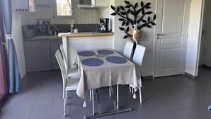 A compact kitchen with a dining area, a white door, and a decorative wall piece. - Cottage in Bourbonnais countryside with private garden (Meillard)