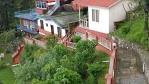A hillside property with multiple buildings, including a main house with a red roof and a smaller structure with a blue roof. - Hotel Galaxy View Tower (Baluwapati Deupur)