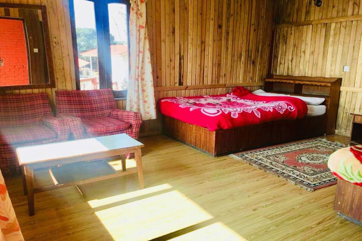 A wooden-paneled room with a bed, a sofa, and a small table.