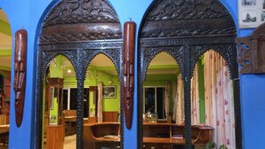 A room with ornate wooden furniture, a mirror with intricate carvings, and a green wall. - Hotel Galaxy View Tower (Baluwapati Deupur)
