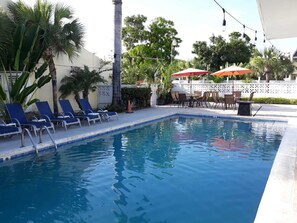Una piscina al aire libre, sombrillas, sillones reclinables de piscina
