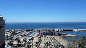 A marina with boats docked, a beach area with umbrellas, and a clear view of the sea. - Fantastic 2 bed 2 bath beachside penthouse with pool and parking (Marbella)