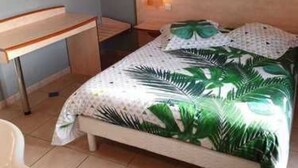 Een slaapkamer met een bed, een bureau en een nachtkastje.