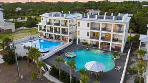 A multi-story hotel with a rooftop pool area, including a hot tub and lounge chairs. - 30A Retreat - 2 Homes, Gulf Views, Great for Large Groups! (Santa Rosa Beach)