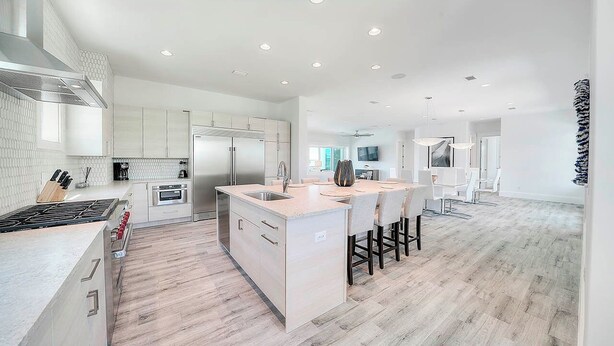 A modern kitchen with a central island, stainless steel appliances, and a wooden floor. - 30A Retreat - 2 Homes, Gulf Views, Great for Large Groups! (Santa Rosa Beach)