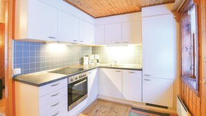 Una cocina compacta con gabinetes blancos, horno empotrado, pileta y salpicadero de azulejos.