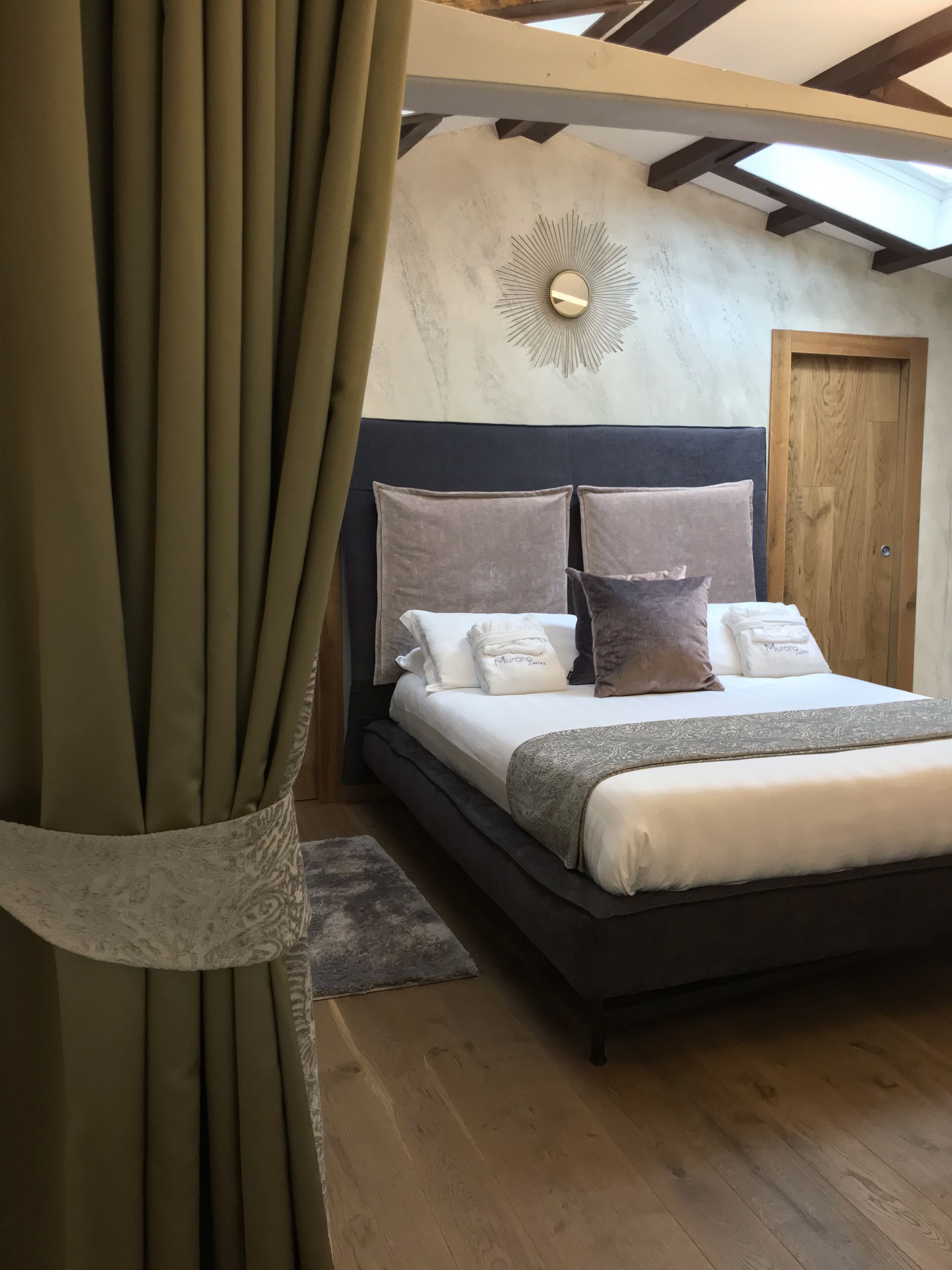 Ein Schlafzimmer mit einem großen Bett, einem dunklen Kopfteil und einer Holztür.