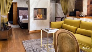 Een gezellige woonkamer met een open haard, een bank, een bed en een keukenhoek.
