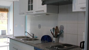 A kitchen with white cabinets, a double sink, a stove, and a coffee maker.
