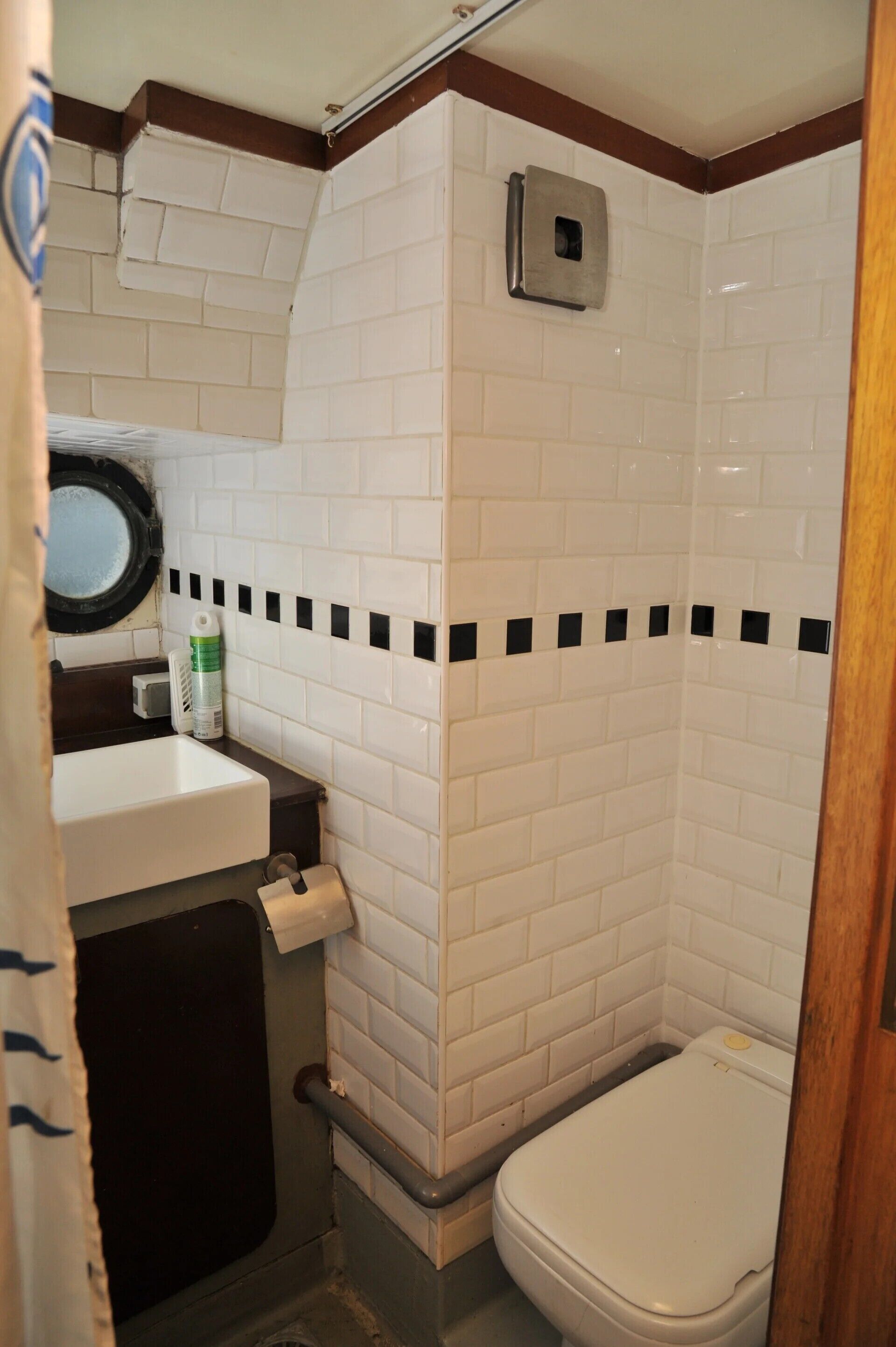 Une petite salle de bain avec des carreaux blancs, des toilettes, un lavabo et un espace douche.