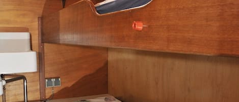 A bunk bed with a wooden headboard, a small window, and a wall-mounted light fixture.