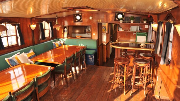 Un intérieur en bois avec un espace bar, des sièges rembourrés de couleur verte et une cuisine.