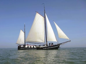 A sailboat with multiple sails, a mast, and a crew on board.